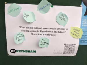 A poster bearing the question: "What kind of cultural events would you like to see happening in Keynsham in the future? Share it on a sticky note!" Several sticky notes read: carnival, museum, craft days, street food markets, repair cafe, etc